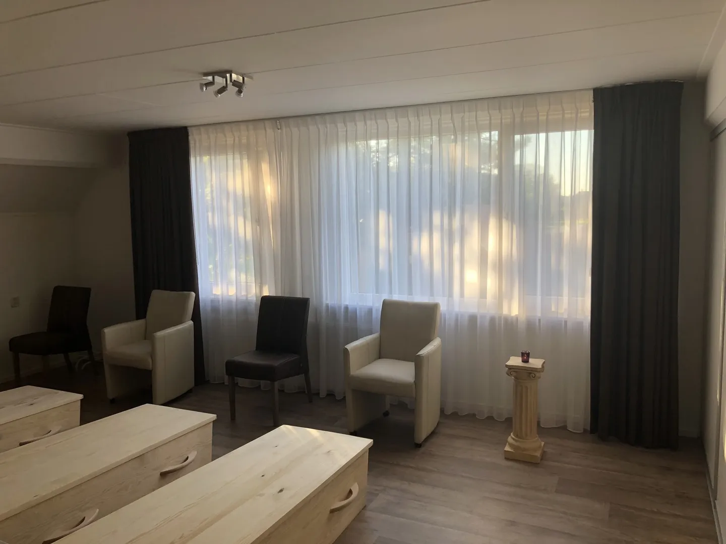 The memento mori seminar room in May 2018: armchairs in a circle by the window, wooden coffins for the coffin meditation in the foreground